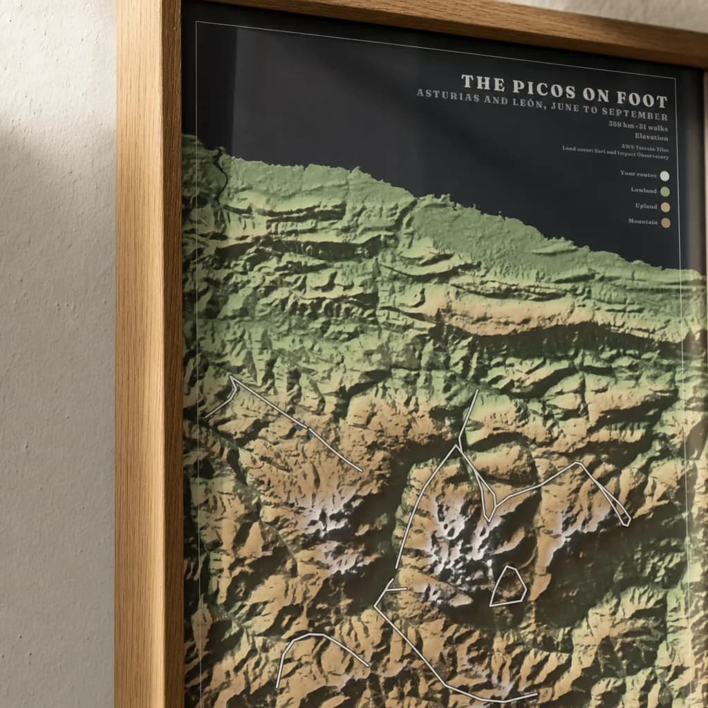Close-up of the corner of the framed slate Picos poster: natural-oak moulding, acrylic glazing straight over the sheet with no mount, and the poster’s own dark margin running to the rebate.