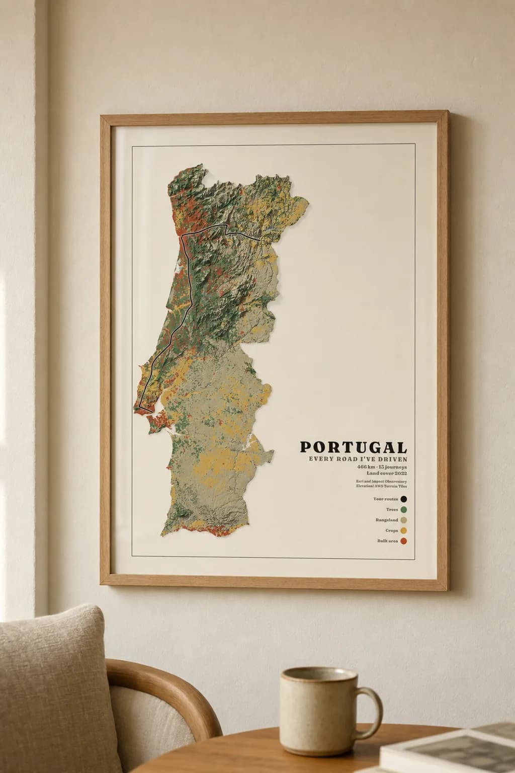 A poster of a Portuguese road trip, framed in oak above a linen armchair
